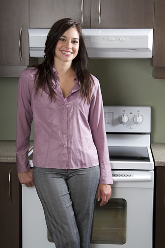young woman standing in front of a kitchen range and range hood